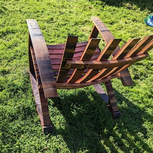 Puede incluir: Una mecedora de madera hecha de barriles de vino reutilizados. La silla tiene un acabado de madera natural y est&aacute; dise&ntilde;ada con un respaldo y brazos de listones.