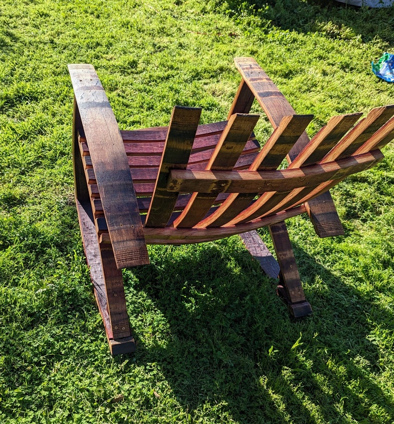 Puede incluir: Una mecedora de madera hecha de barriles de vino reutilizados. La silla tiene un acabado de madera natural y est&aacute; dise&ntilde;ada con un respaldo y brazos de listones.