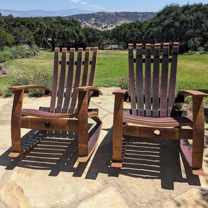 Puede incluir: Dos mecedoras de madera hechas con barriles de vino reutilizados. Las sillas son marrones con detalles morados y est&aacute;n colocadas en un patio de piedra. Las sillas se enfrentan y est&aacute;n en una posici&oacute;n relajada.