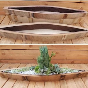 May include: Two wooden planters made from repurposed wine barrels. The planters are shaped like a boat and are made of natural wood with a dark brown stain. The planters are empty in the top image and filled with succulents in the bottom image.
