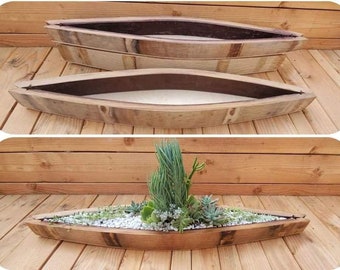 May include: Two wooden planters made from repurposed wine barrels. The planters are shaped like a boat and are made of natural wood with a dark brown stain. The planters are empty in the top image and filled with succulents in the bottom image.