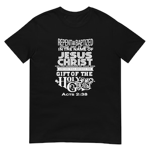 Op de afbeelding: Zwart T-shirt met witte tekst. De tekst bevat de woorden "REPENT" en "BAPTIZED" boven "JESUS CHRIST". Onder de tekst staat "ACTS 2:38". Het shirt is een shirt met korte mouwen en een ronde hals.