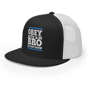 Op de afbeelding: Zwarte en witte truckerpet met de tekst "OBEY ACTS 2:38 BRO IM JUST SAYIN'" in wit en blauw. De pet heeft een zwarte klep en voorpaneel, met een witte mesh achterkant.