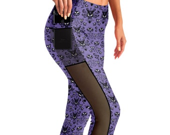 May include: Purple leggings with a black and white pattern of a haunted house. The leggings have a mesh panel on the side and a pocket on the left leg.