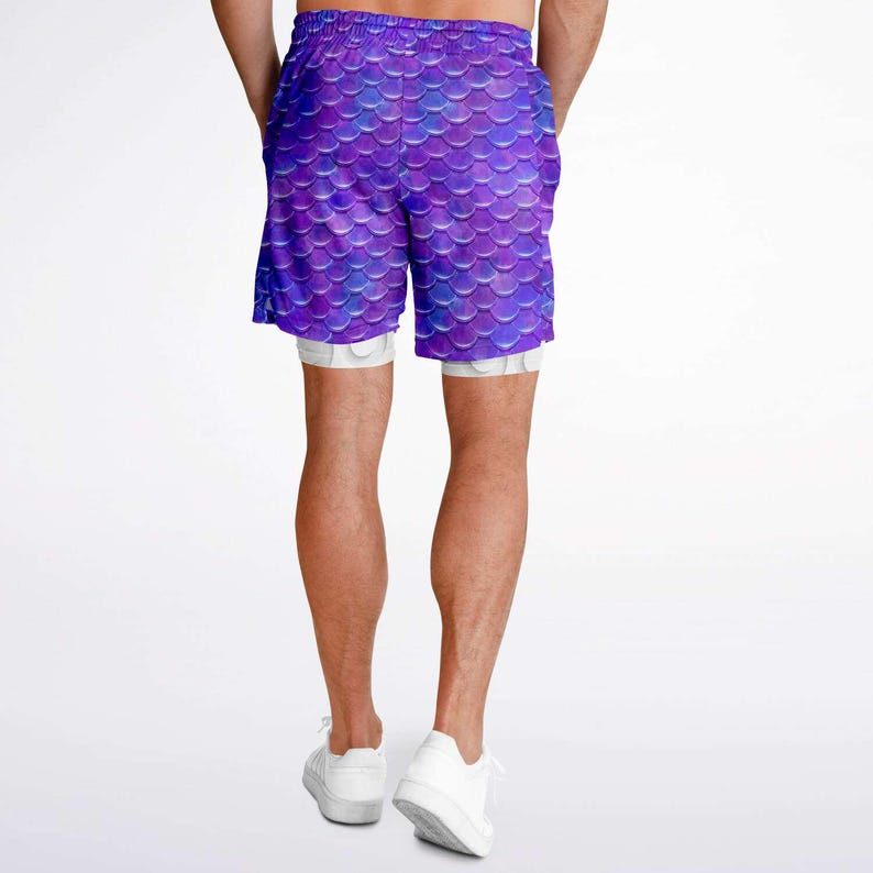 Puede incluir: Pantalones cortos deportivos de color morado con un patr&oacute;n de escamas de sirena. Los pantalones cortos tienen un forro interior blanco y est&aacute;n hechos de una tela ligera y transpirable.