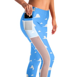 Pode incluir: Leggings azuis com um padrão de nuvens brancas e um painel de malha no lado. As leggings têm um bolso na perna esquerda.