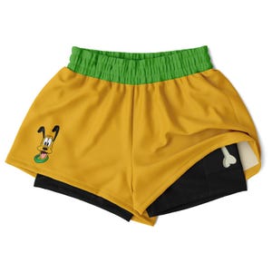 May include: Yellow athletic shorts with a green waistband and a cartoon dog graphic. The shorts have a black lining with a white bone graphic.