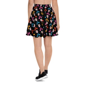 May include: A black skater skirt with a colorful skull and crossbones pattern. The skirt is knee-length and has a flared silhouette.