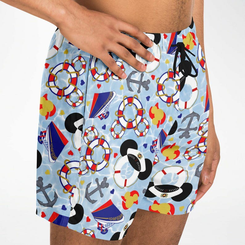 K&ouml;nnte beinhalten: Hellblaue Badeshorts mit nautischem Muster. Die Shorts zeigen rot-wei&szlig;-blaue Rettungsringe, Anker, Matrosenm&uuml;tzen und Herzen. Der Hintergrund hat einen wasser&auml;hnlichen Effekt.