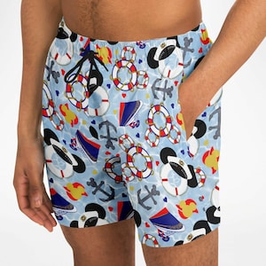K&ouml;nnte beinhalten: Hellblaue Badeshorts mit nautischem Muster. Das Design umfasst Anker, Rettungsringe, Matrosenm&uuml;tzen und Mickey Mouse-f&ouml;rmige Elemente. Die Shorts haben einen Kordelzug und Taschen.