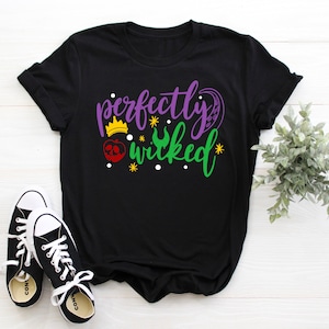 May include: Black t-shirt with a purple and green graphic that says "perfectly wicked" with a crown, apple, and crescent moon design.