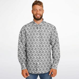 Puede incluir: Una camisa de manga larga con botones y un patrón geométrico en tonos grises y blancos.