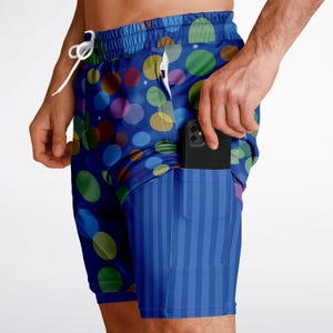 May include: Blue and white patterned swim shorts with a side pocket. The shorts have a colorful polka dot design.