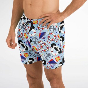 K&ouml;nnte beinhalten: Hellblaue Badeshorts mit nautischem Muster. Die Shorts zeigen Anker, Rettungsringe und Bootsillustrationen in Rot, Wei&szlig; und Blau. Sie haben einen schwarzen Kordelzug.