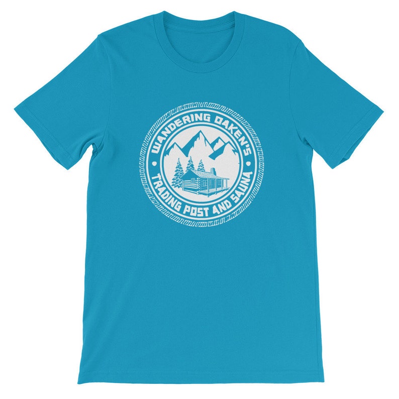 May include: A turquoise blue t-shirt with a white circular logo. The logo features a cabin in the woods with mountains in the background. The text "Wandering Daken's Trading Post and Sauna" is written around the logo.