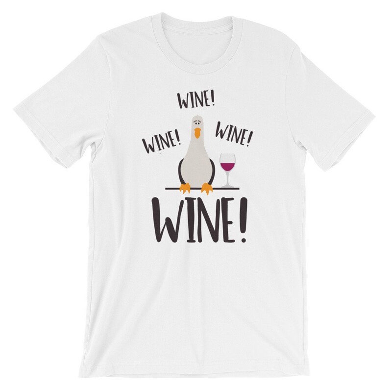May include: White t-shirt featuring a cartoon bird holding a glass of wine. The shirt has the text "WINE!" repeated four times.
