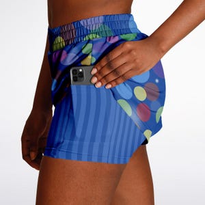 May include: Blue and white athletic shorts with a colourful polka dot pattern. The shorts have a built-in pocket on the side, ideal for holding a phone.