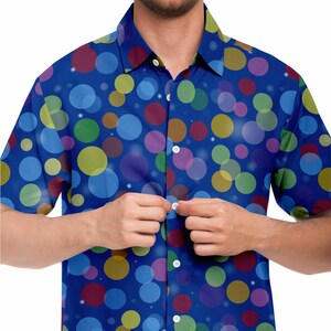 May include: A blue short-sleeved button-down shirt with a colorful polka dot pattern. The shirt has a white button placket and white buttons.