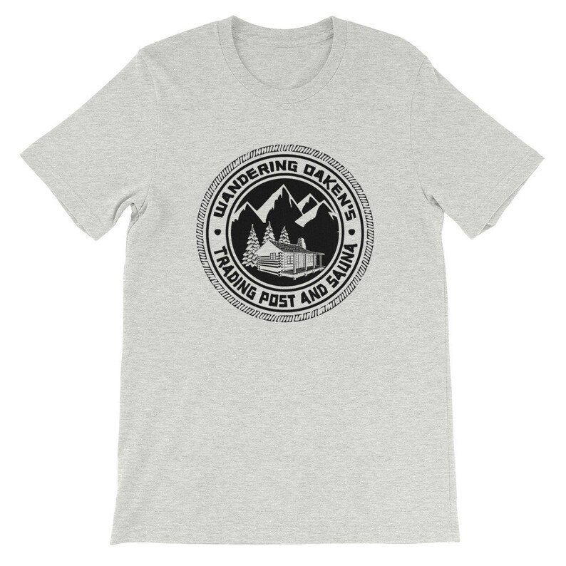 May include: A gray t-shirt with a black and white logo that says "Wandering Daken's Trading Post and Sauna". The logo features a cabin in the mountains.