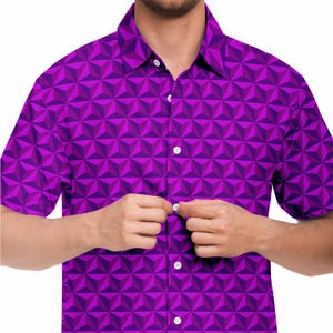 May include: A purple short-sleeved button-down shirt with a geometric pattern.