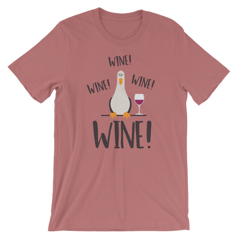 May include: A pink t-shirt featuring a cartoon seagull holding a glass of wine. The shirt has the text "Wine!" repeated four times.