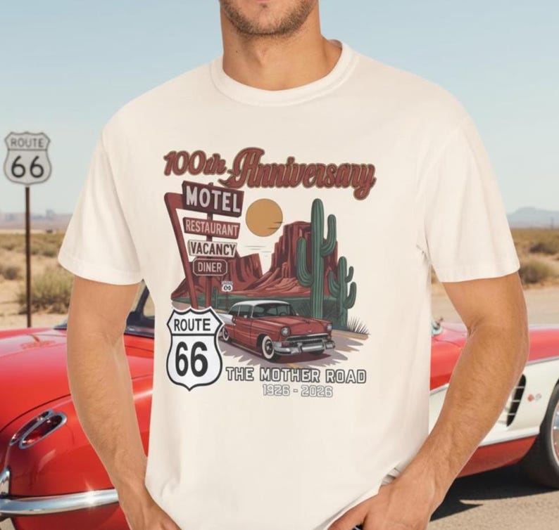 Puede incluir: Camiseta color crema con un dise&ntilde;o de la Ruta 66. El gr&aacute;fico incluye un coche antiguo, un paisaje des&eacute;rtico y el texto "100th Anniversary" y "The Mother Road 1926-2026". Tambi&eacute;n se ve un letrero de la Ruta 66.