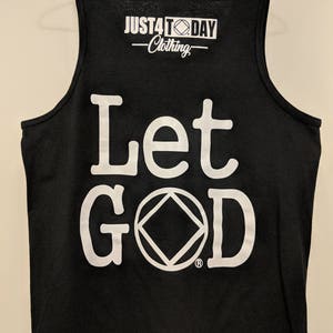 May include: Black tank top with white text that reads "Let God" and a white symbol. The top also has a white logo that reads "JUST4TODAY Clothing".