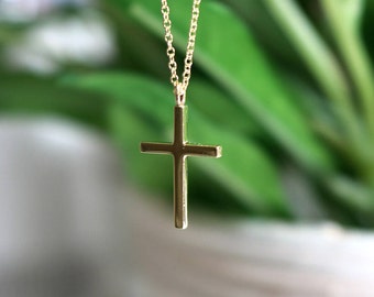 May include: A gold chain necklace with a simple gold cross pendant.