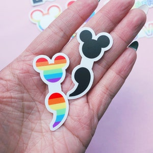 May include: Two semicolon stickers, one with a rainbow design and the other black. Both stickers feature Mickey Mouse ears.