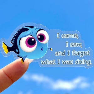 May include: A transparent sticker featuring a cartoon blue fish with large pink and white eyes. The fish has black and yellow accents. Text on the sticker reads, "I came, I saw, and I forgot what I was doing."