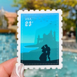 May include: A blue and green sticker featuring a silhouette of a castle and a couple. The sticker has a white border with a perforated edge and the text "USA 23c" in the top left corner.