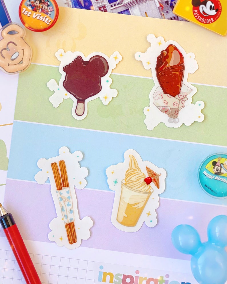 May include: A collection of colorful stickers featuring Disney-themed treats, including a Mickey Mouse-shaped ice cream bar, a turkey leg, churros, and a soft-serve ice cream. Other items include a "1st Visit" pin, a Mickey Mouse-shaped pin, and a "Happy Birthday" pin.