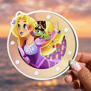 Könnte beinhalten: Ein Aufkleber mit einer Cartoon-Prinzessin mit langen blonden Haaren, die ein lila Kleid trägt, und einem grünen Chamäleon mit Piratenhut. Die Prinzessin befindet sich in einem goldfarbenen Kreis vor einem Sonnenuntergangshintergrund.