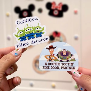 May include: Two stickers featuring characters from the movie Toy Story. One sticker shows three green aliens with the text "OoOoooo, niiice dooooor". The other sticker shows Woody and Buzz Lightyear with the text "A Rootin' Tootin' Fine Door, Partner".