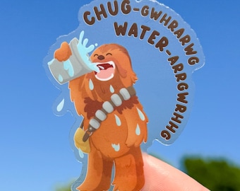 May include: A clear sticker featuring a cartoon depiction of a Wookiee drinking water from a container. The sticker has the text "CHUG-GWHRAWRG WATER-ARRGWRHHG" in a blue bubble around the character. The Wookiee is brown with a bandolier.