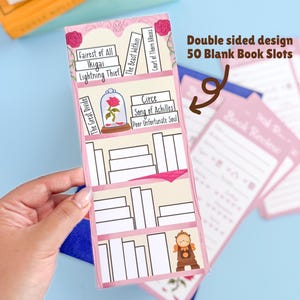 May include: A pink and white book review organizer with the text "Double sided design 50 Blank Book Slots". The organizer has a bookshelf design with book titles and illustrations. The organizer is held by a hand.