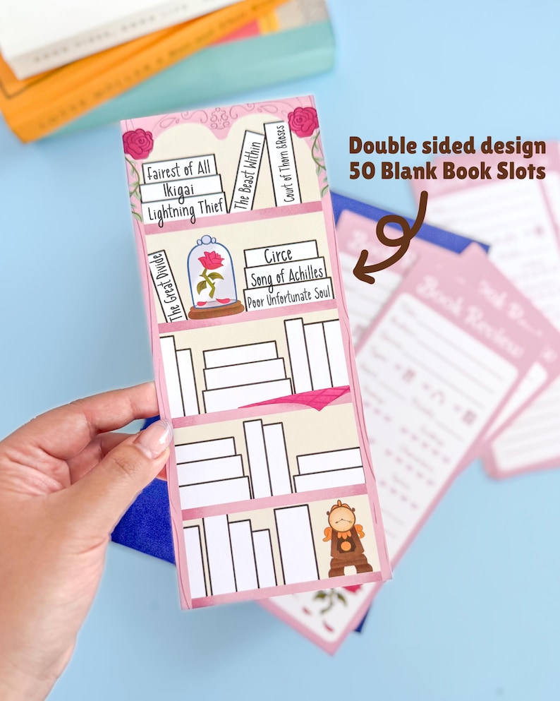 May include: A pink and white book review organizer with the text "Double sided design 50 Blank Book Slots". The organizer has a bookshelf design with book titles and illustrations. The organizer is held by a hand.