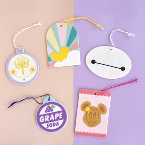 May include: Five colourful paper tags with string attached. The tags feature various Disney characters and designs, including Mickey Mouse, Baymax, a grape soda logo, and a design with a castle and fireworks.