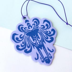 May include: A purple car air freshener with a blue floral design. The air freshener is hanging from a purple string.
