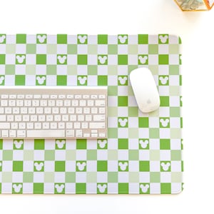 May include: A green and white checkered mouse pad with a white mouse and a white keyboard. The mouse pad has a pattern of white Mickey Mouse heads on a green background.