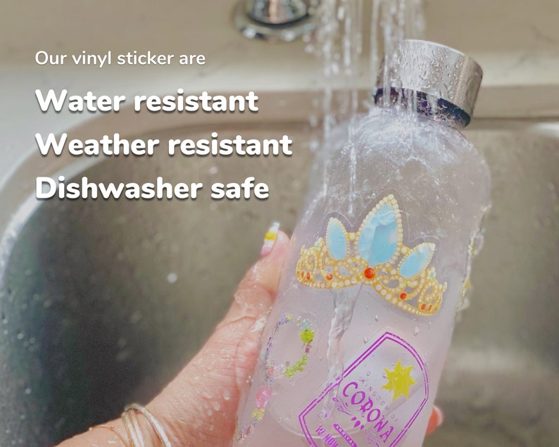 May include: A clear glass bottle with a silver lid and a colorful sticker featuring a crown and the word "Corona". The bottle is being rinsed under running water in a kitchen sink. The text "Our vinyl sticker are Water resistant Weather resistant Dishwasher safe" is visible at the top of the image.