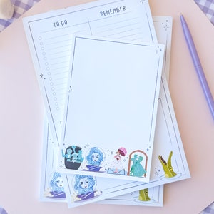 Puede incluir: Un conjunto de tres blocs de notas blancos con un dise&ntilde;o caprichoso que presenta personajes de la atracci&oacute;n Haunted Mansion de Disneyland. Los blocs de notas tienen una secci&oacute;n "To Do" y "Remember". El dise&ntilde;o incluye un fantasma, un cocodrilo y una pareja bailando.