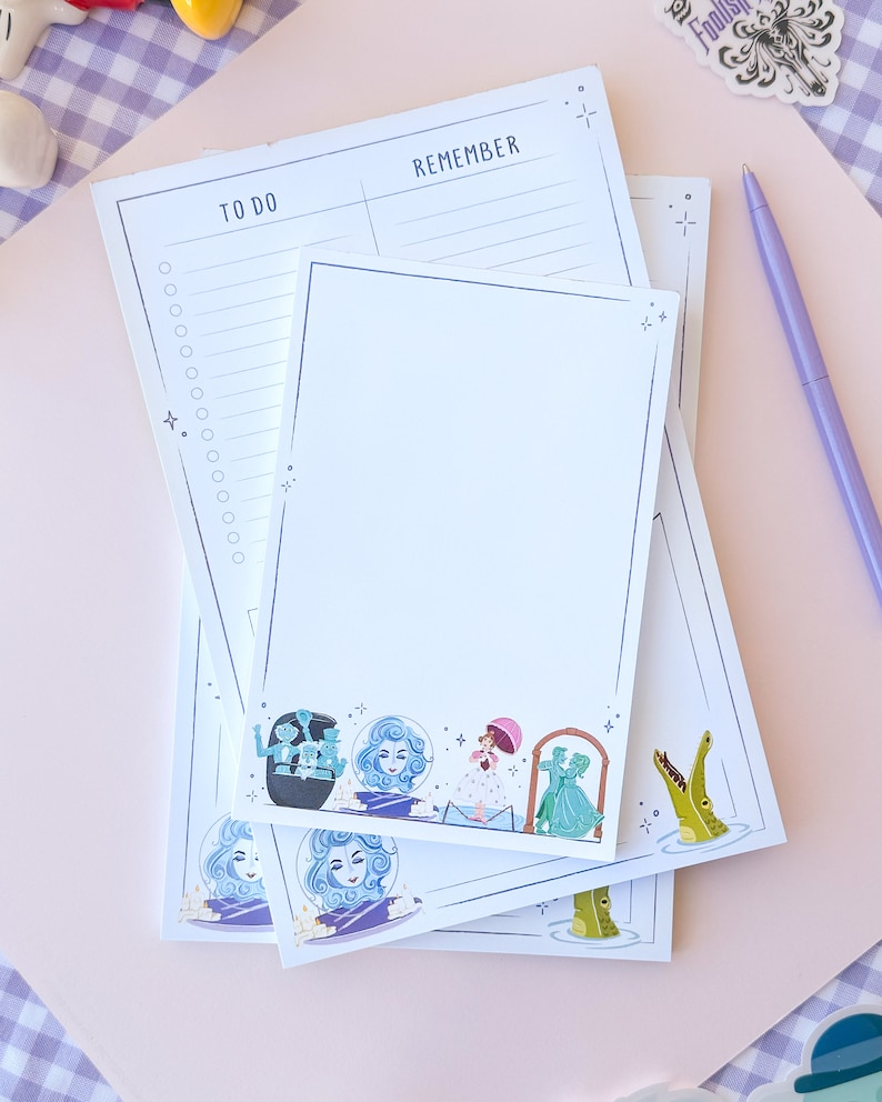 Puede incluir: Un conjunto de tres blocs de notas blancos con un dise&ntilde;o caprichoso que presenta personajes de la atracci&oacute;n Haunted Mansion de Disneyland. Los blocs de notas tienen una secci&oacute;n "To Do" y "Remember". El dise&ntilde;o incluye un fantasma, un cocodrilo y una pareja bailando.
