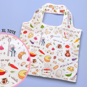 Op de afbeelding: Witte tote bag met een kleurrijk cartoonpatroon van eten en een muis-kok. De tekst op de tas zegt "Le petit chef" en "wish upon magic".
