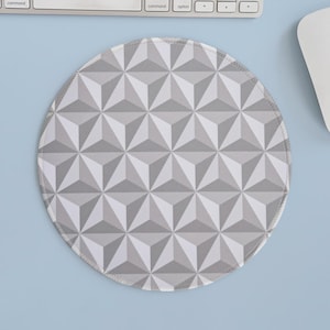 May include: Round mousepad with a geometric pattern of gray and white triangles. The mousepad has a light gray border and is on a light blue surface. A computer keyboard and mouse are partially visible in the background.