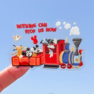 May include: A clear sticker featuring a red train with Mickey Mouse, Minnie Mouse, Pluto, and Goofy. The train has a blue engine and the text "NOTHING CAN STOP US NOW" in red.
