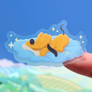 May include: A clear sticker featuring a cartoon illustration of a yellow dog sleeping on a blue cloud with white stars.