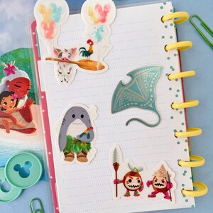 Pu&ograve; includere: Un set di cinque adesivi colorati con personaggi del film Disney Moana. Gli adesivi includono un maiale con un gallo sulla schiena, uno squalo con una collana di fiori, una manta e due piccoli personaggi con lance.