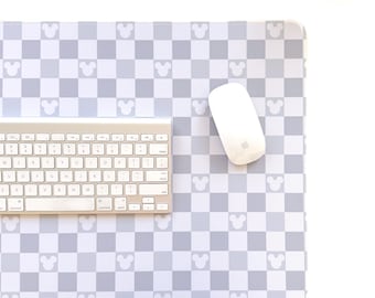 May include: A gray and white mousepad with a checkered pattern and Mickey Mouse head silhouettes. A silver keyboard and white mouse are on the pad. The mousepad is rectangular.