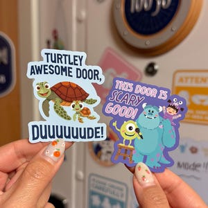 Pode incluir: Dois adesivos coloridos são exibidos. Um apresenta uma família de tartarugas de desenho animado com o texto "TURTLEY AWESOME DOOR, DUUUUUUDE!". O outro mostra personagens de desenho animado com o texto "THIS DOOR IS SCARY GOOD!".